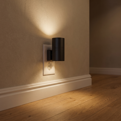 Vega lit in a wall socket by the skirting board in a hallway, warm light washing up the wall and out across the floor